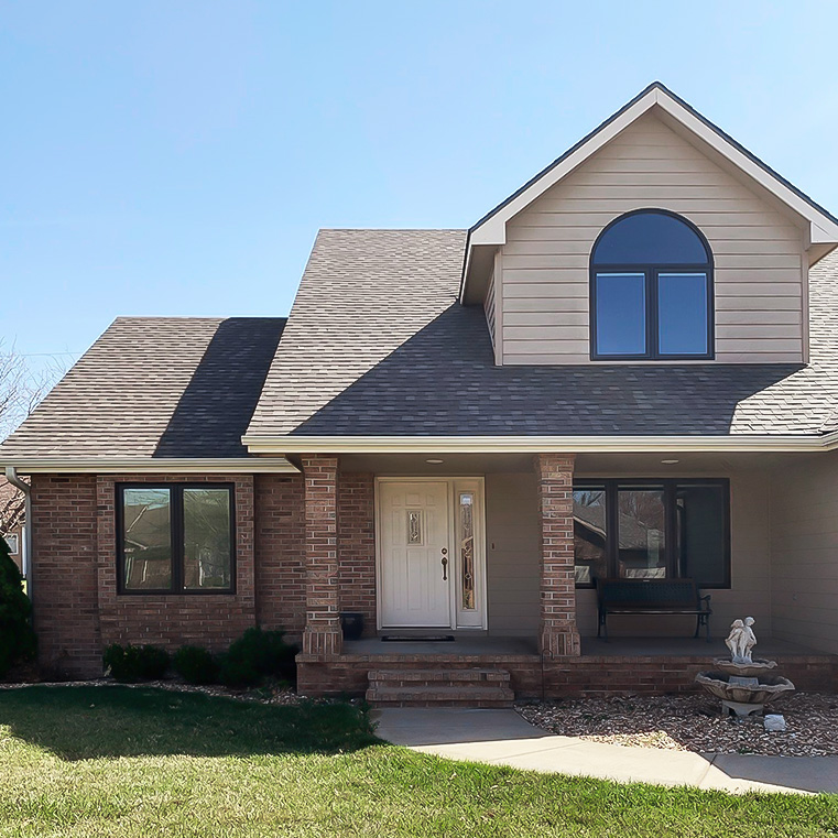 A modern home exterior featuring a sloped roof and casement windows, surrounded by a green lawn.