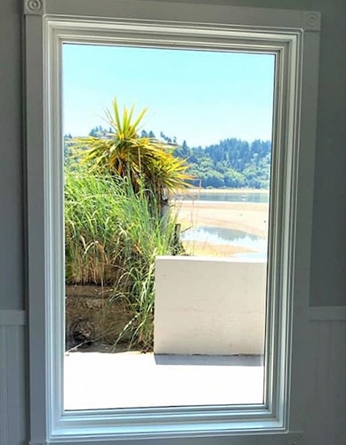 Tall white casement window looking out to an ocean view