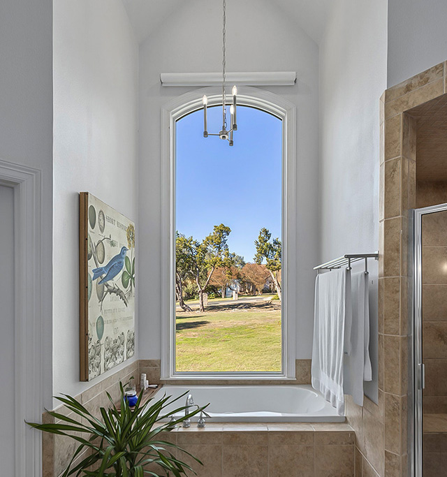  Elegant bathroom with tall window above bathtub bringing in natural light.
