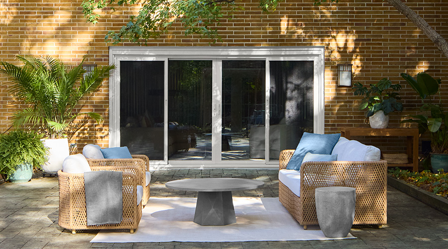 White sliding patio doors opening to an outdoor seating area against a brick exterior.
