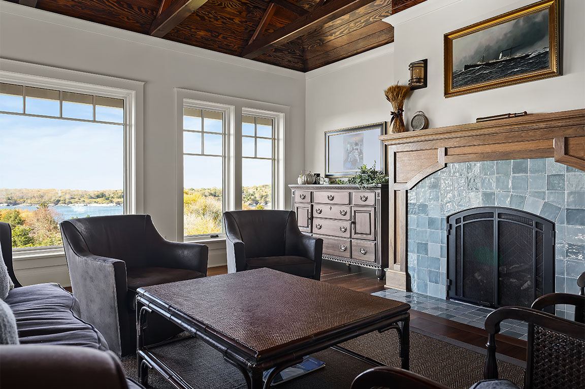 Living room with fireplace, wood windows, and scenic outdoor view.