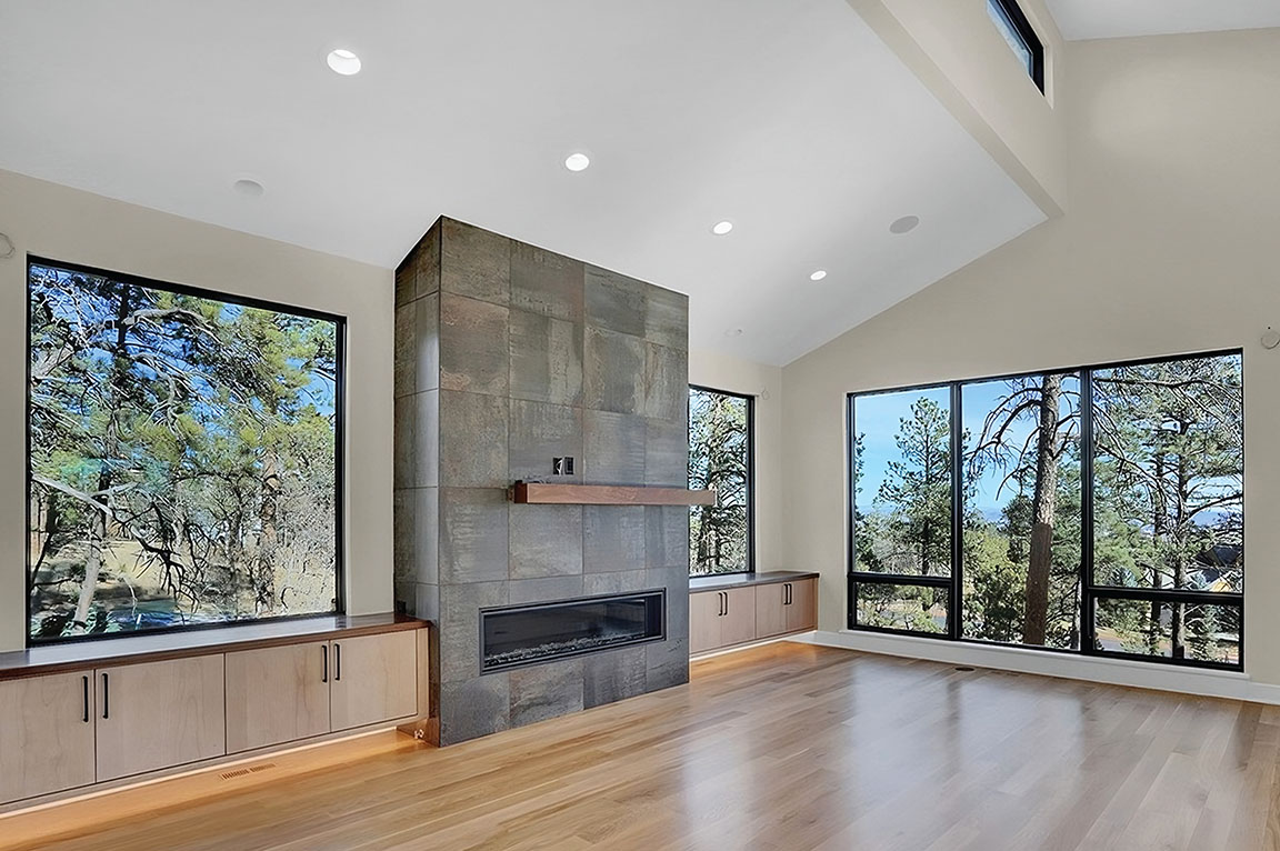 A spacious great room featuring a modern fireplace and large windows with scenic views.