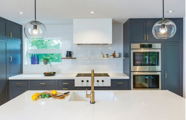 Modern kitchen with charcoal cabinets, white countertops & windows, and gold accents