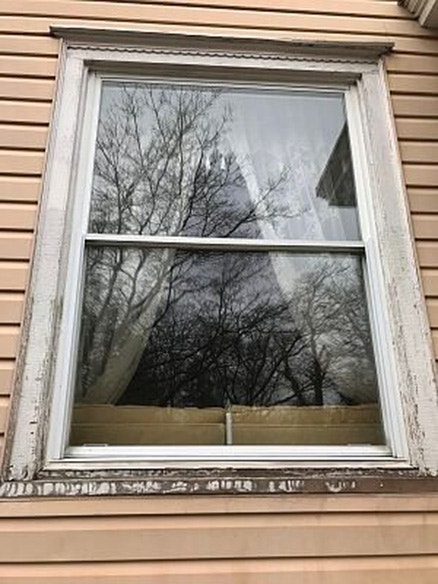 Before image of a historic wood window with white frame