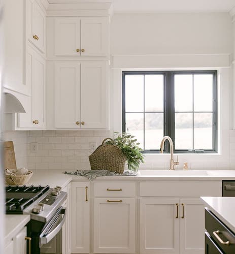 Two black casement windows above the kitchen sink match the cabinet color on the kitchen island.