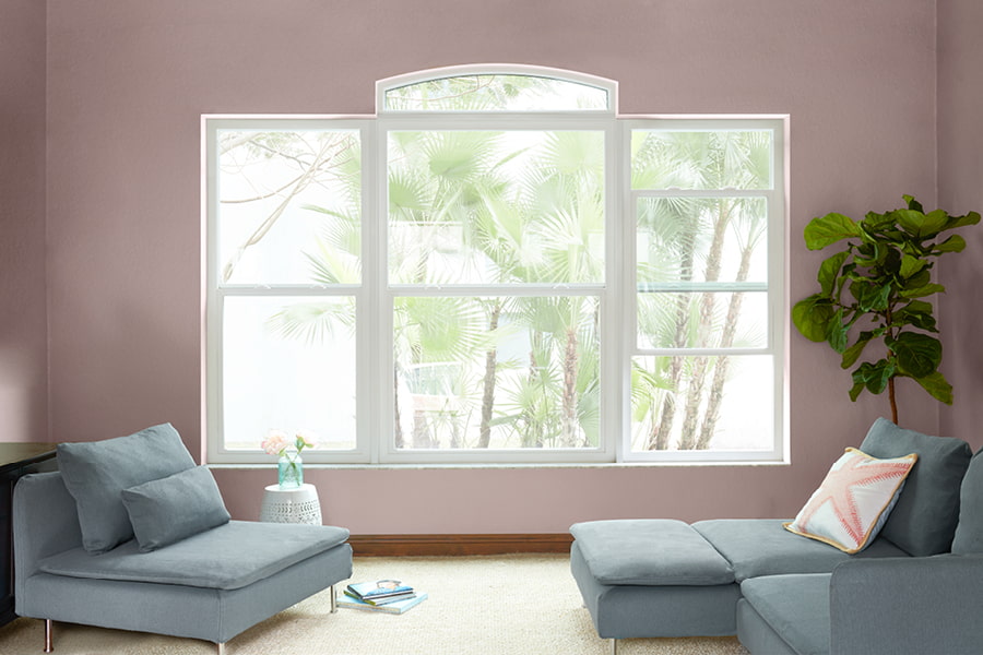 3 white framed windows with a transom in a pink living with green furniture