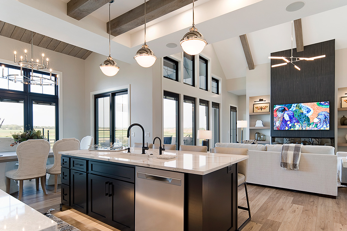 A modern kitchen with a black island and marble countertops, featuring new construction windows and an open concept design.