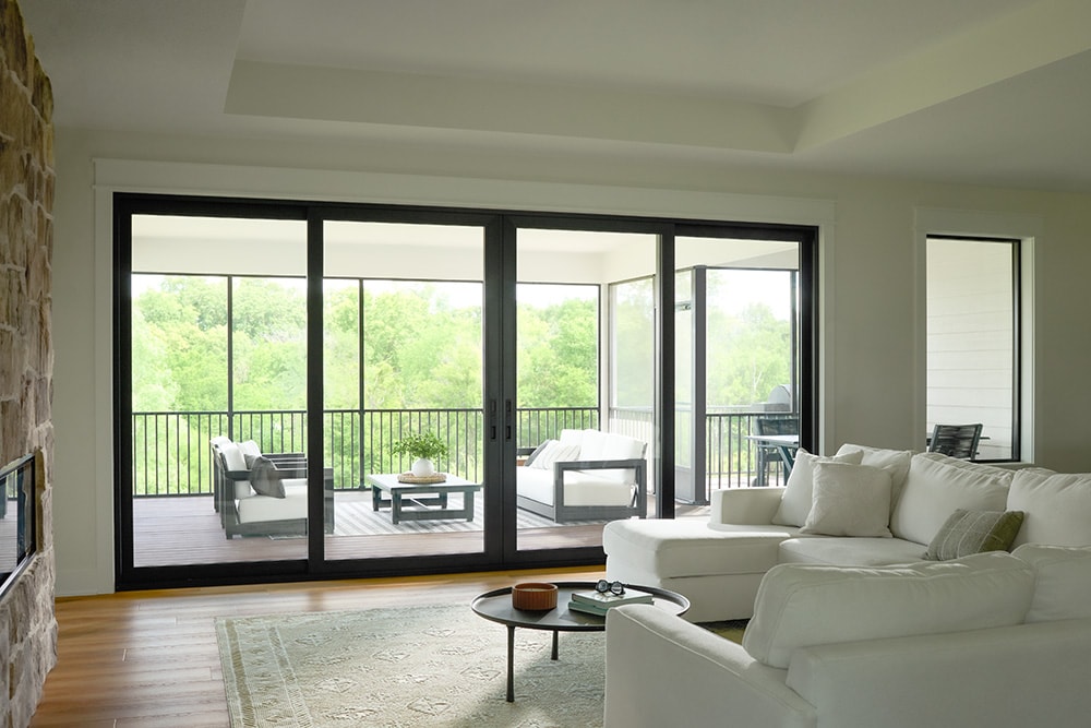 Bright living room with white sectional and large black sliding glass doors opening to a balcony.