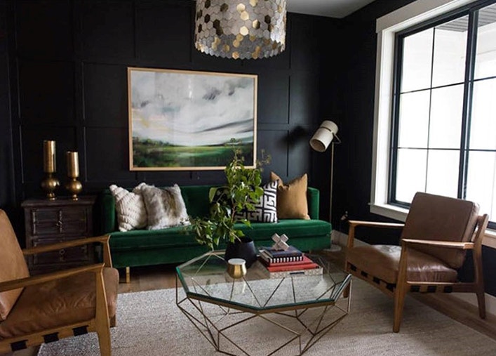 large black windows light living room with black walls, green couch, and brown leather chairs