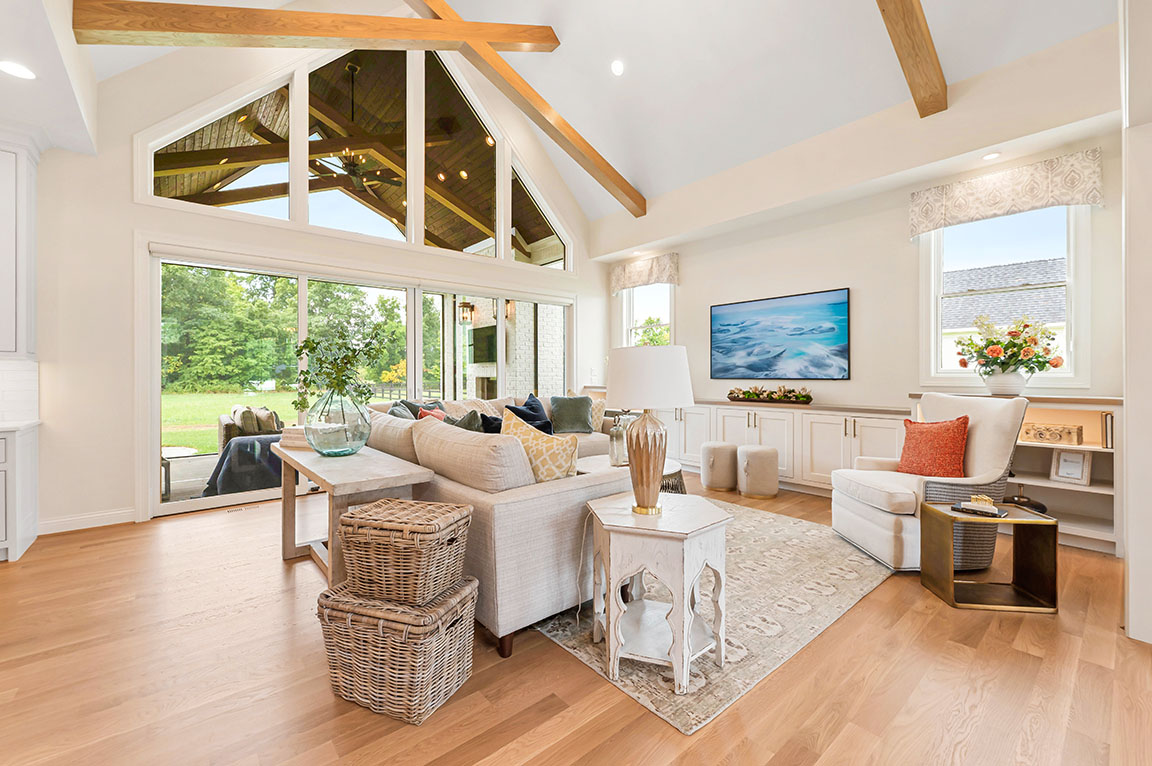 Bright living room with vaulted ceiling, wood beams, large windows, and cozy sectional sofa 