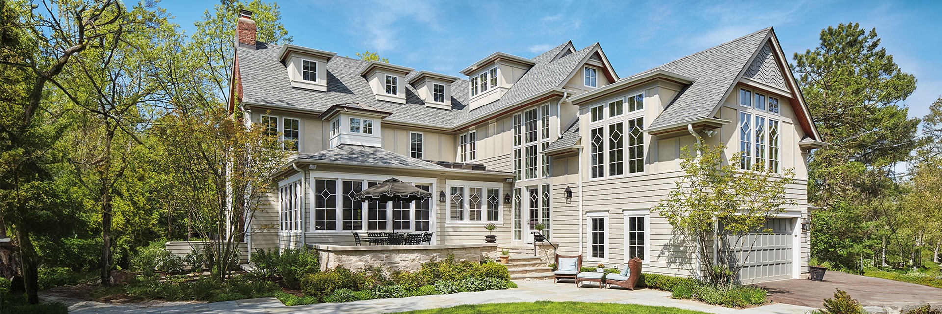 A large home in New York filled with windows and a walkout deck off the back door.