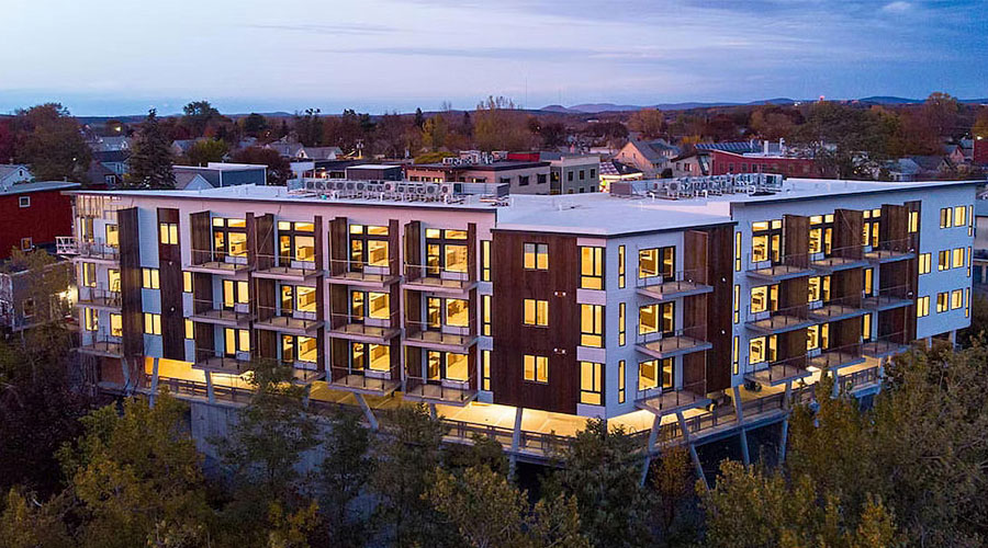 An apartment building at dusk set in a natural environment.