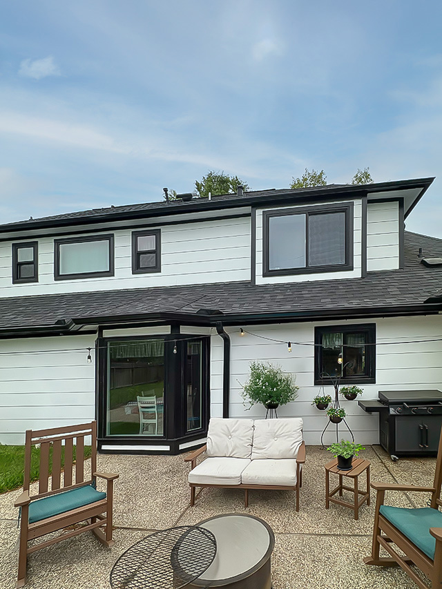 Olde Oak home with white siding, bay window, and patio seating area.