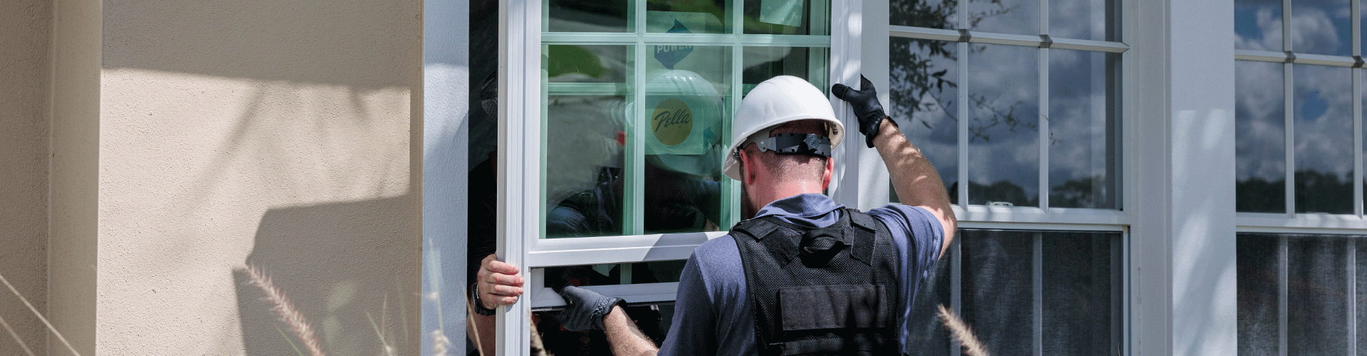 two home construction workers installing power by pella windows