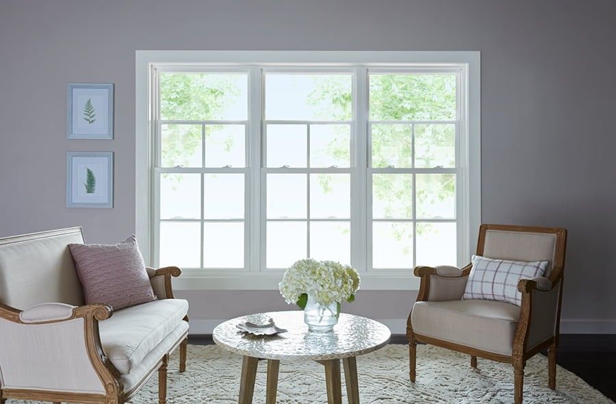 Three white double-hung windows side-by-side on a pale pink wall in a living or drawing room