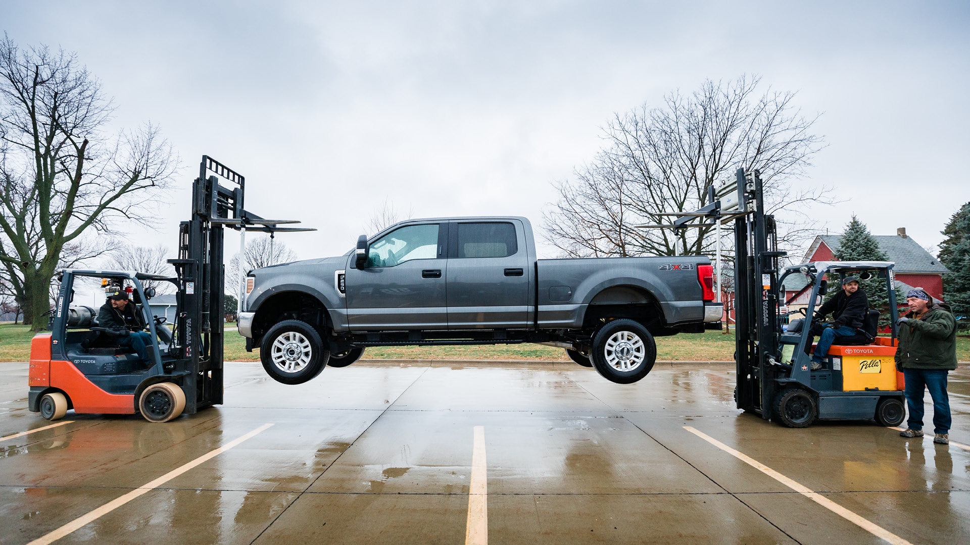 a pickup truck hanging on two impervia sills being upheld by forktrucks