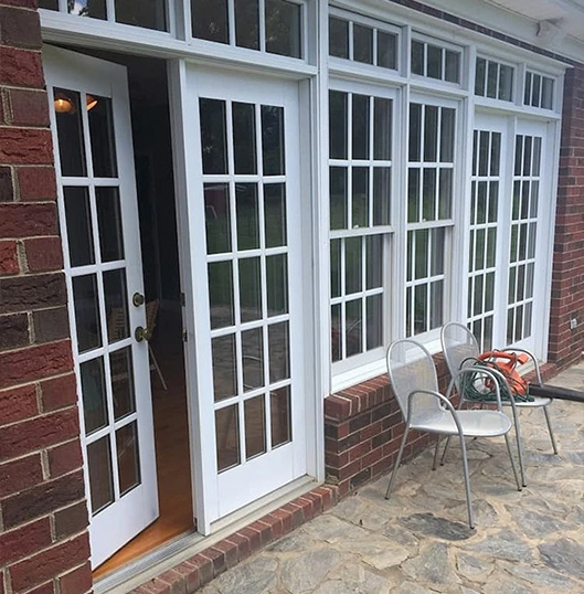 a white hinged door with double-hung windows on a brick home exterior