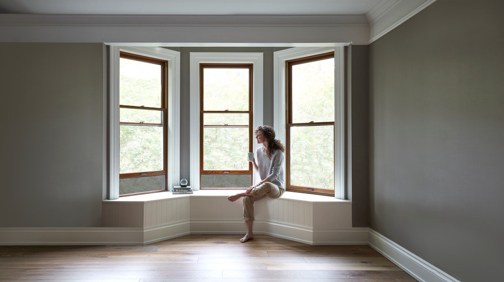 Wood stain bay windows with white trim and woman sitting on window seat