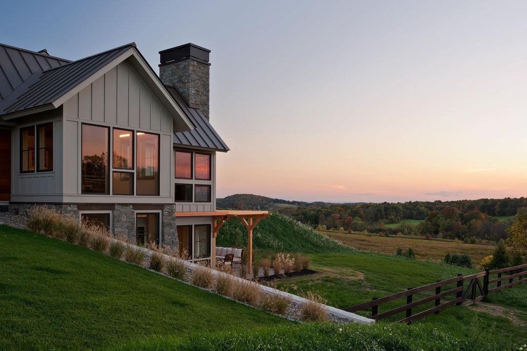 This farmhouse exterior with basement windows sits among the hills of the countryside. 