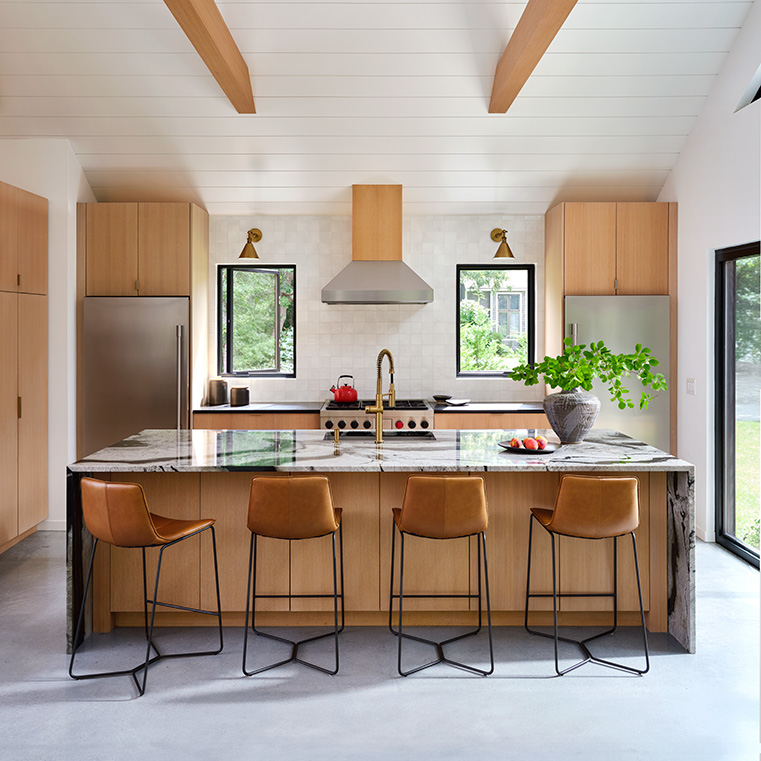 A modern kitchen with black windows, wooden cabinets, and a large island with bar stools.