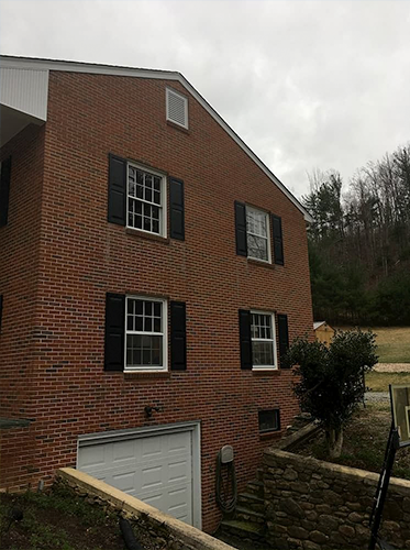 large brick home with white windows and a below-ground garage