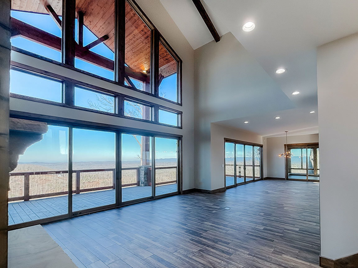Open living room with floor‑to‑ceiling windows and scenic views.