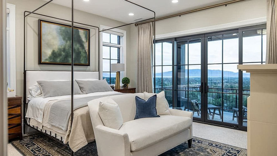 Black french doors open from this Utah master bedroom to a small outer deck