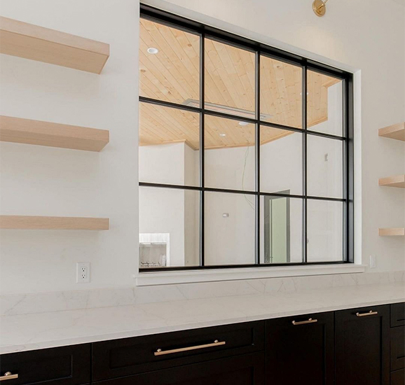 a large black picture window sits over a long kitchen counter