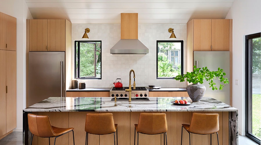 A large kitchen island sits in front of two black casement windows