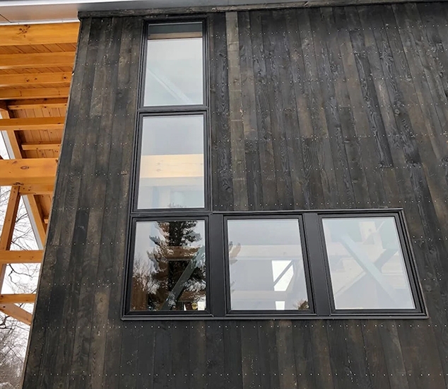 Close up view of durable black Pella windows newly installed on a Hinesburg cabin.