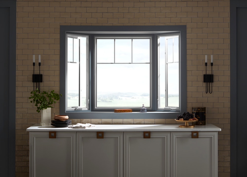 Bay window with white frames and blue trim directly above kitchen counter