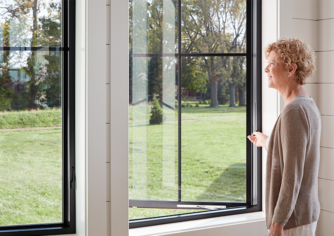 a woman is opening a casement window using the new easy-slide operator