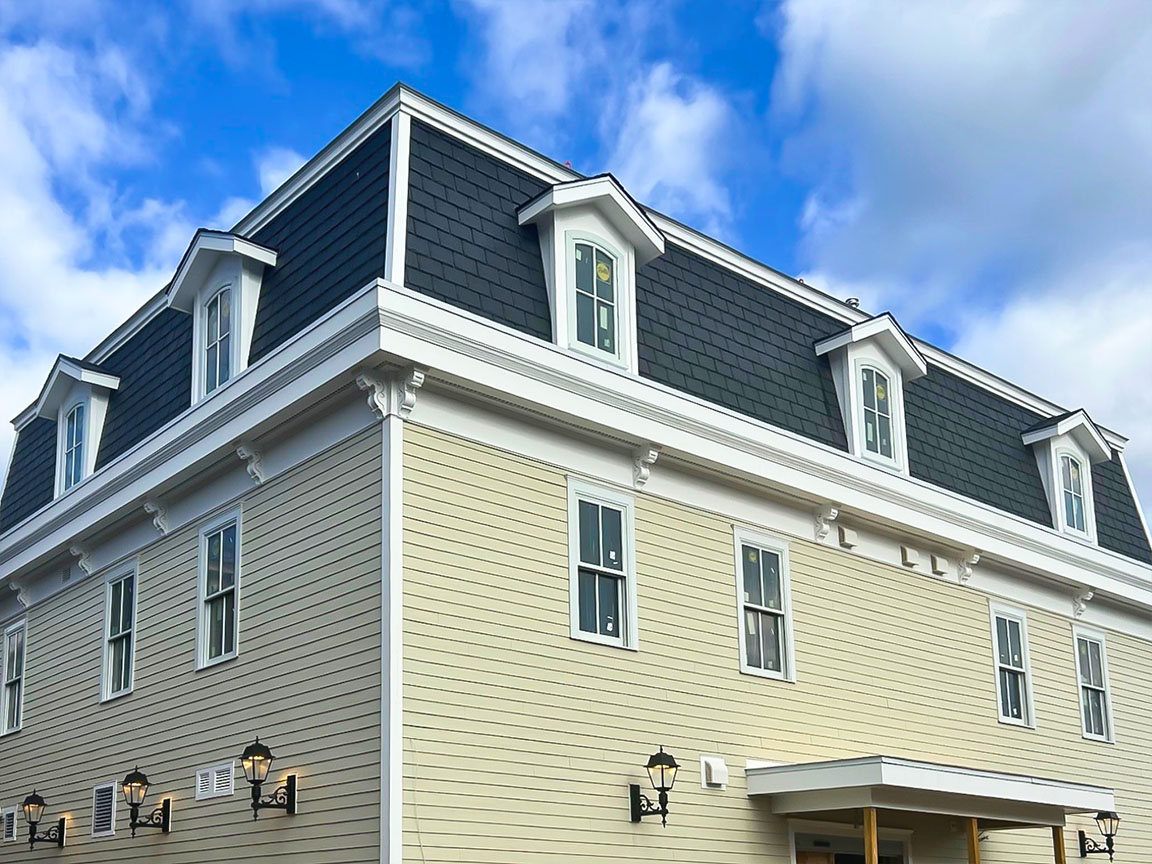 Corner view of restored historic building featuring mansard roof and dormer windows.