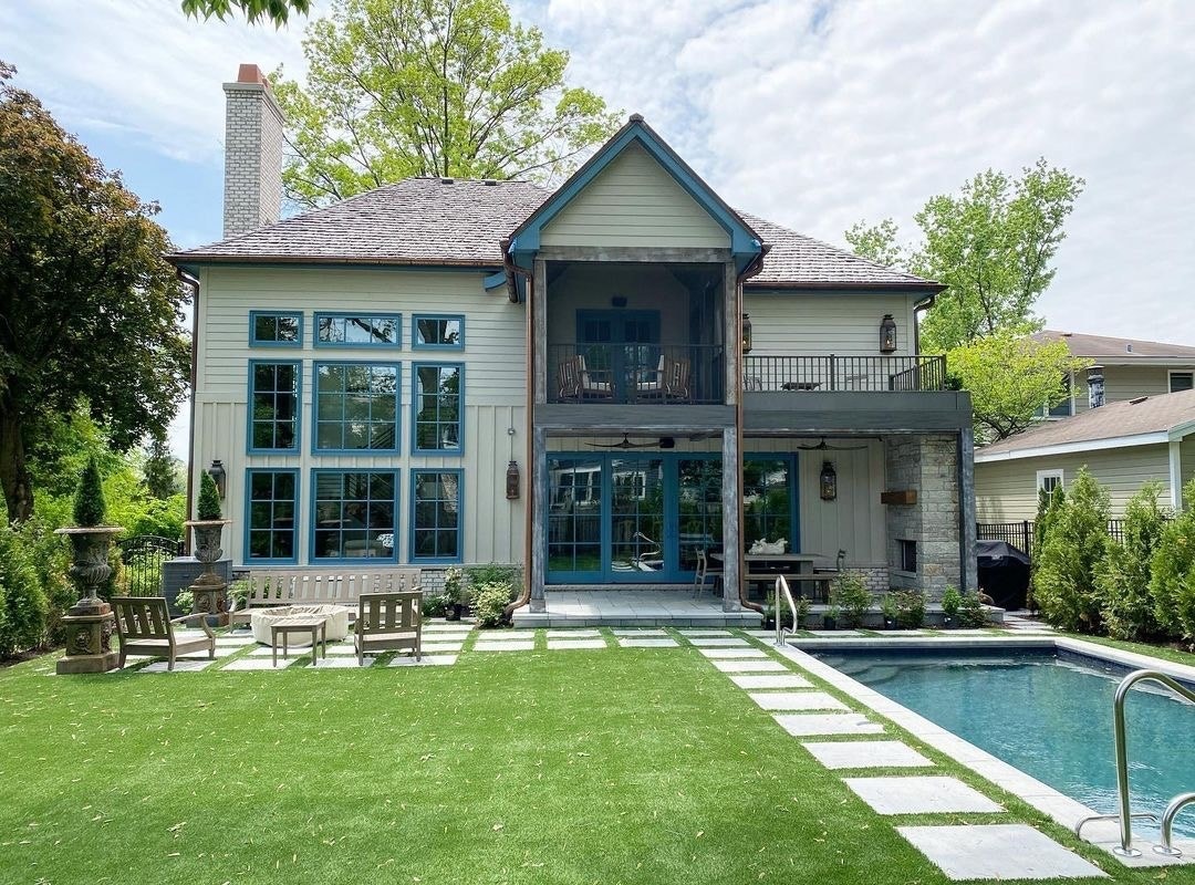 The exterior of this home features blue windows and patio doors, looking over a pool.