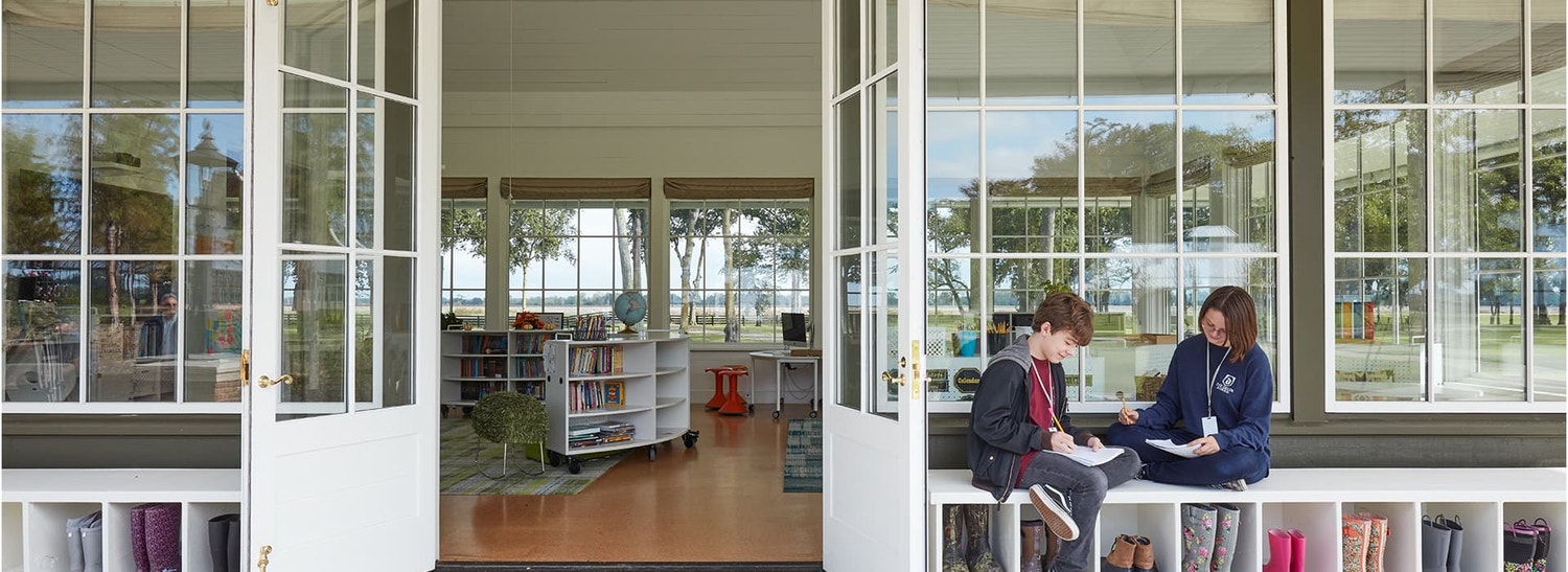 two children sitting outside a school library with pella windows and doors