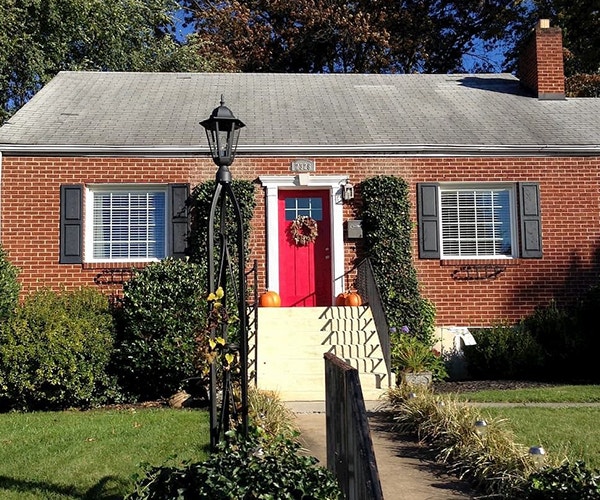 Brick cape cod-style home with a red front door