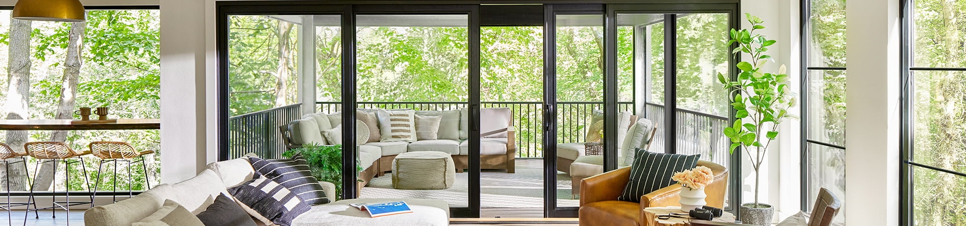 a contemporary living room features a four-panel black wood sliding patio door opening to a luxurious back deck