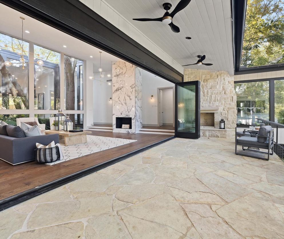 Black glass bifolding doors completely open a wall between the living room and outdoor patio.
