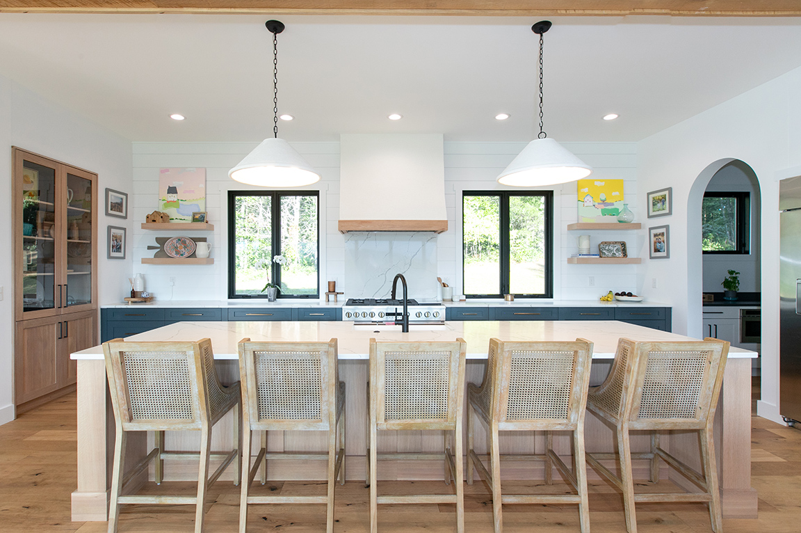 Modern farmhouse kitchen featuring two black windows on either side of the range hood. 