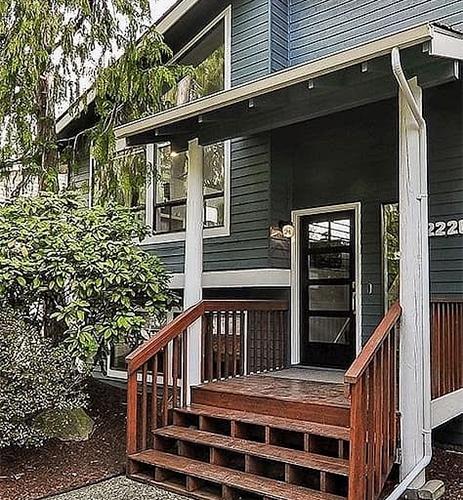 A northwestern home with a redwood front porch and a black contemporary front entry door