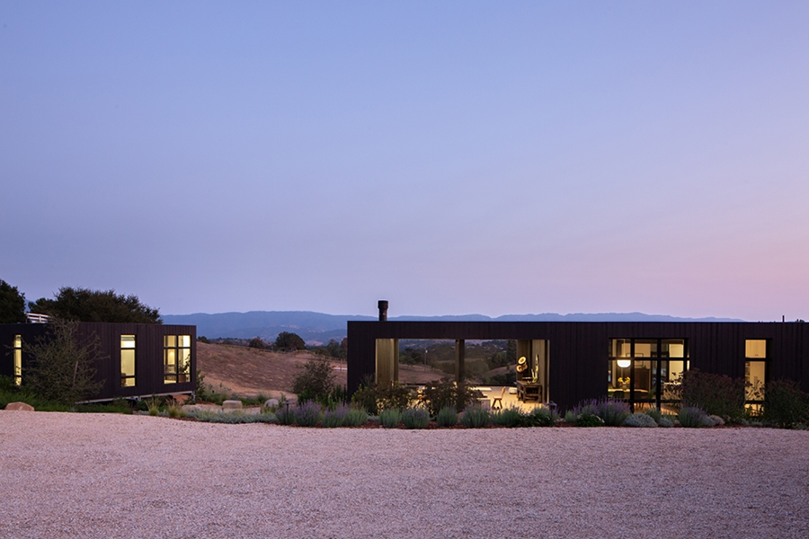 Sunrise sky with desert landscape and a building with a window wall and black frame windows