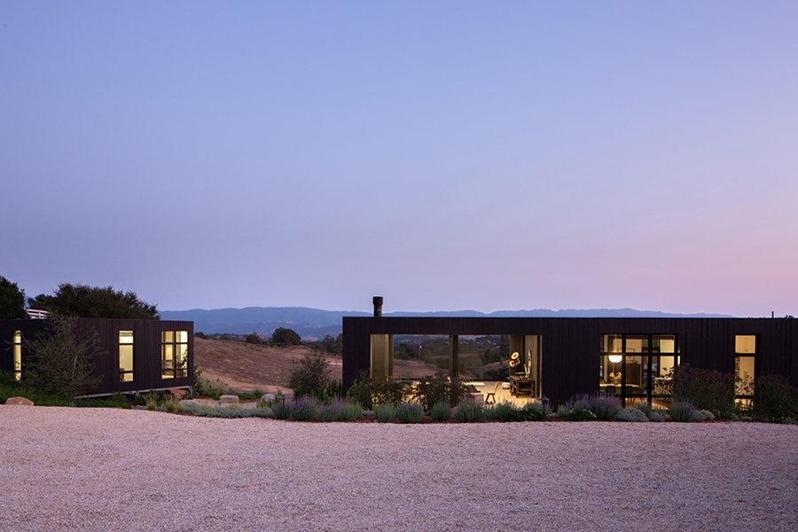 Sunrise sky with desert landscape and a building with a window wall and black frame windows