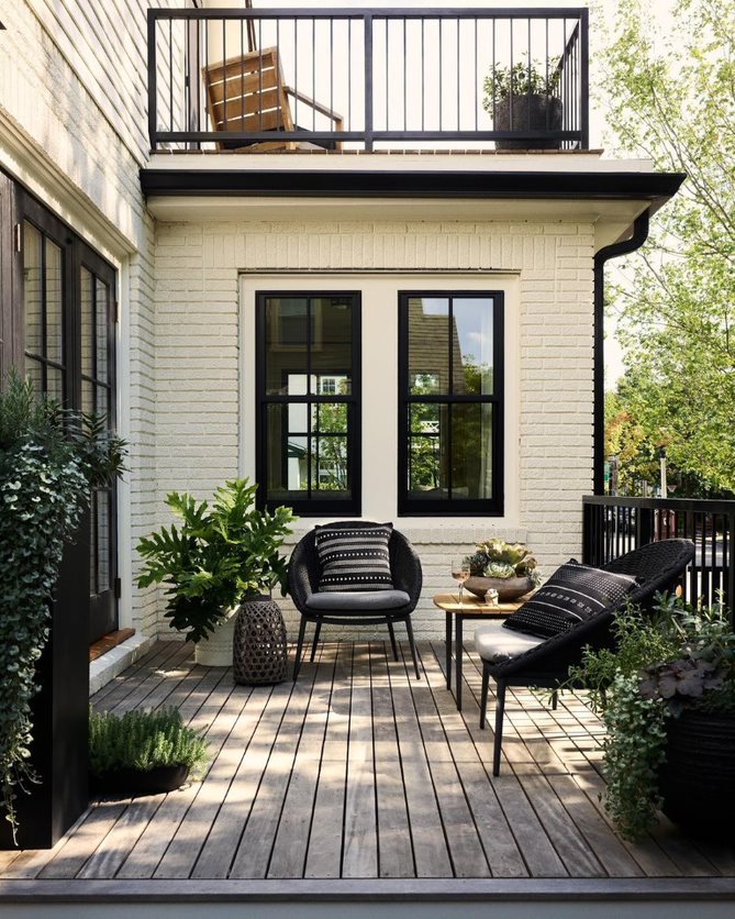 The exterior of a white home showcases black double-hung windows on a modern-style deck.