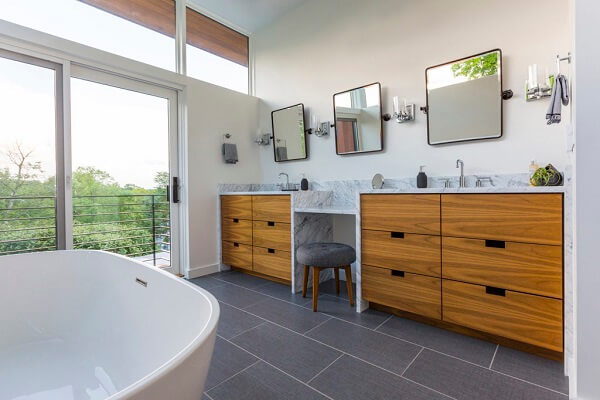 Modern bathroom with wood double vanities and wall of glass with fixed windows and sliding patio door