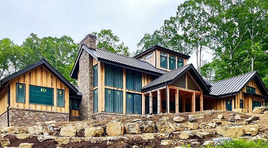 the back exterior of a large wood home with floor-to-ceiling windows