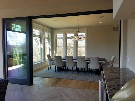 formal white dining room connected to covered patio by black mult-slide patio door