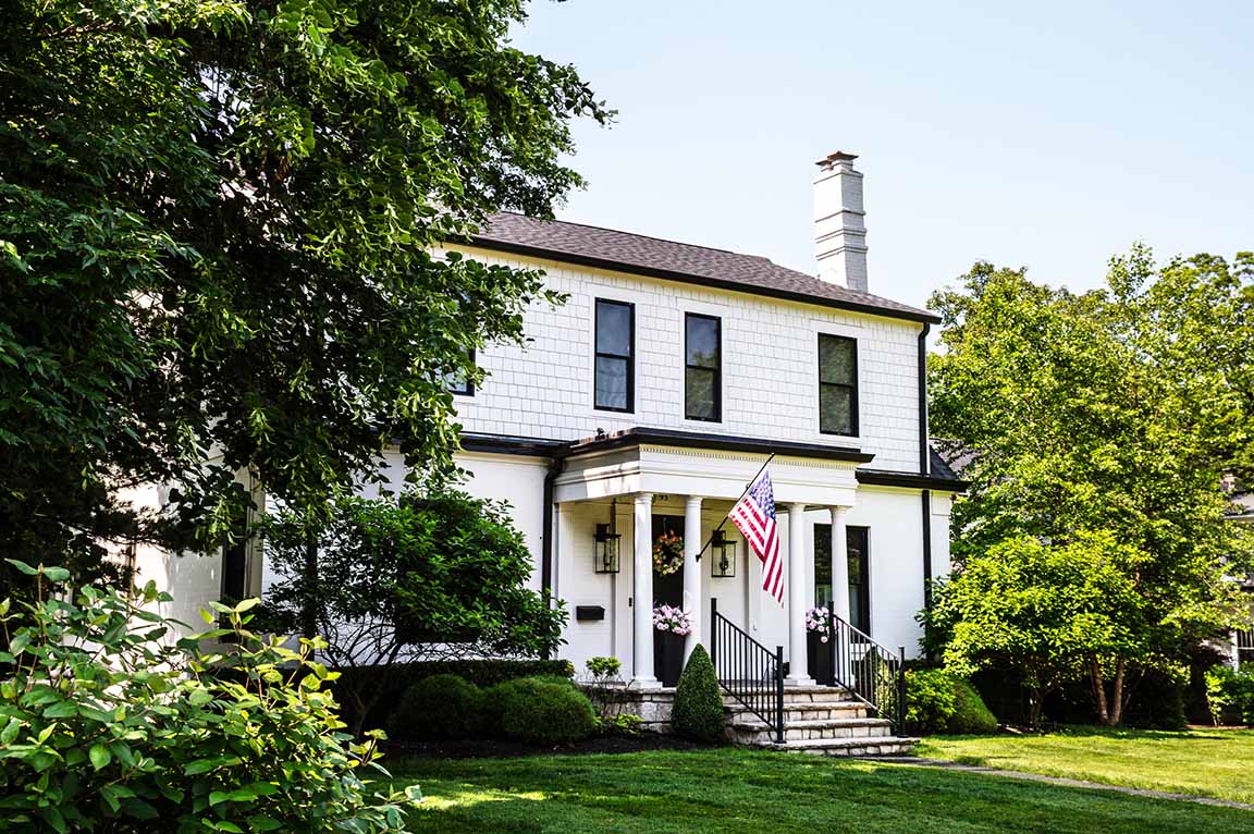 Columbus Worthington home with white siding and a columned entrance displaying an American flag.