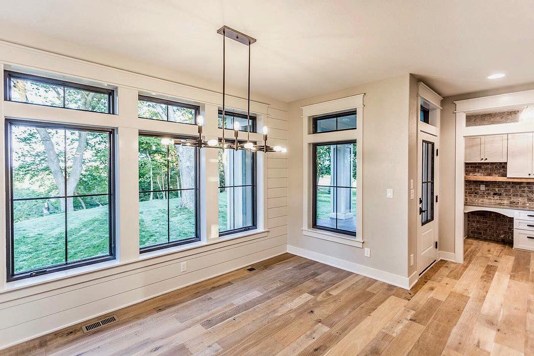 black window frames with white trim in a room with shiplap walls and wood flooring