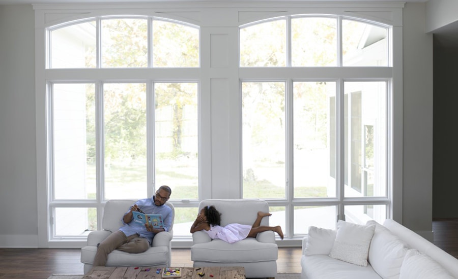 A father and daughter enjoy some time together in front of a window wall, featuring Pella Lifestyle Series windows.