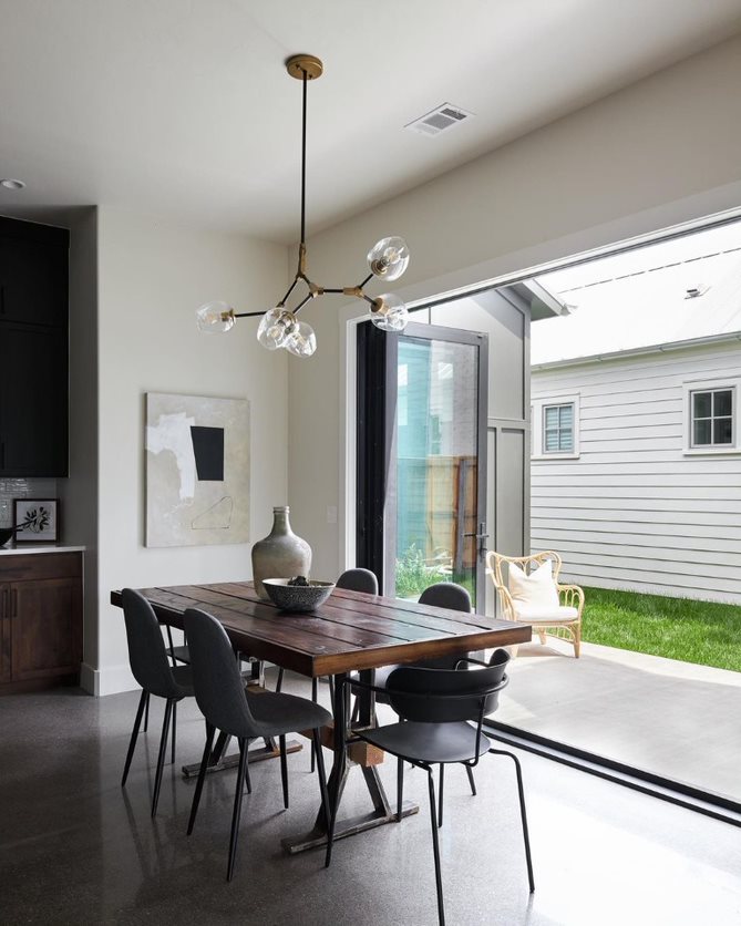 A black folding glass door leads from the modern dining room to the backyard.